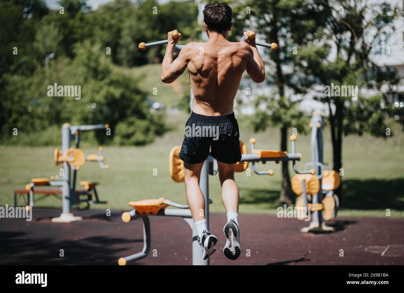 Back view of a muscular man doing pull-ups at an outdoor gym Stock ...