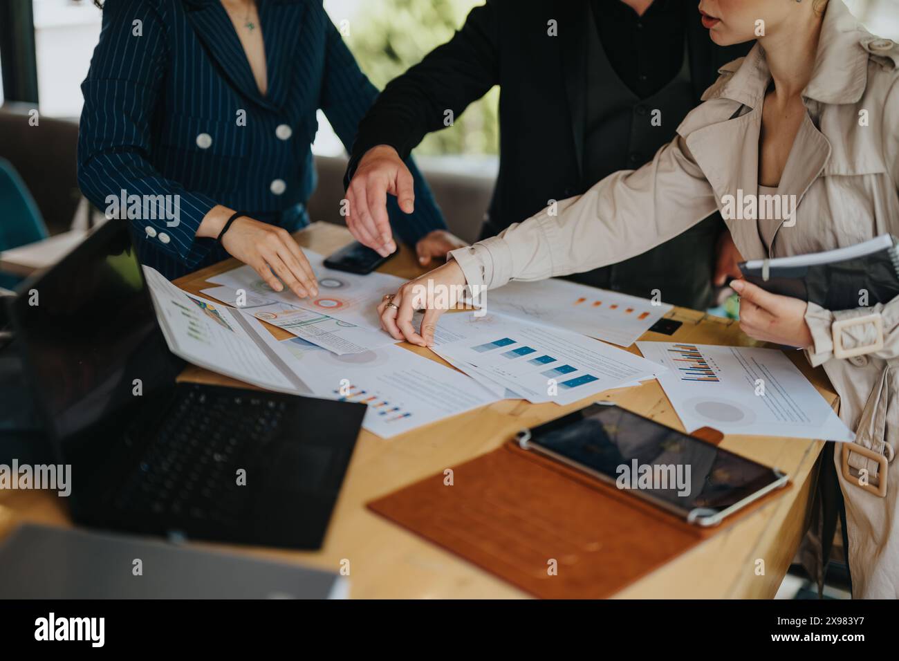 Business team collaborating on project, analyzing data and charts on table Stock Photo