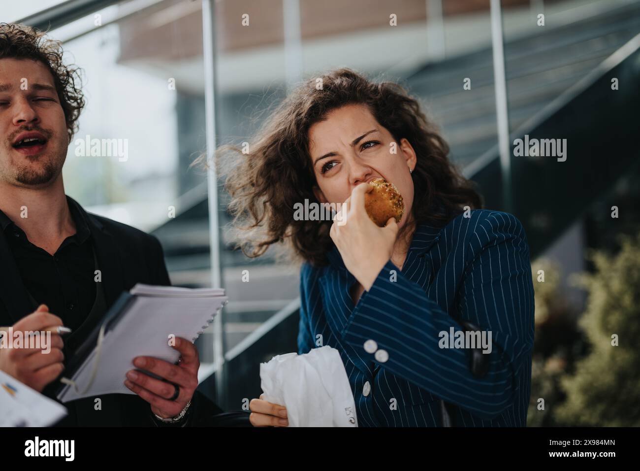 Business professionals discussing work while enjoying a quick lunch break outdoors Stock Photo