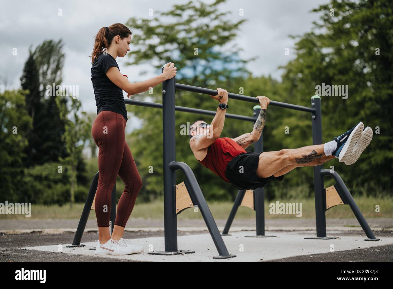 Fitness enthusiasts performing exercises on horizontal bars in a lush ...