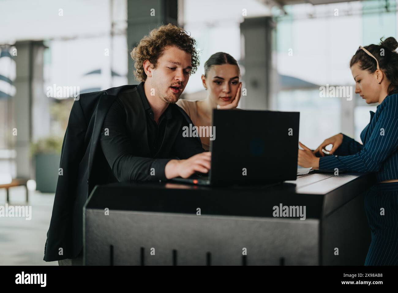 Group of young professionals working together on a laptop in a modern ...