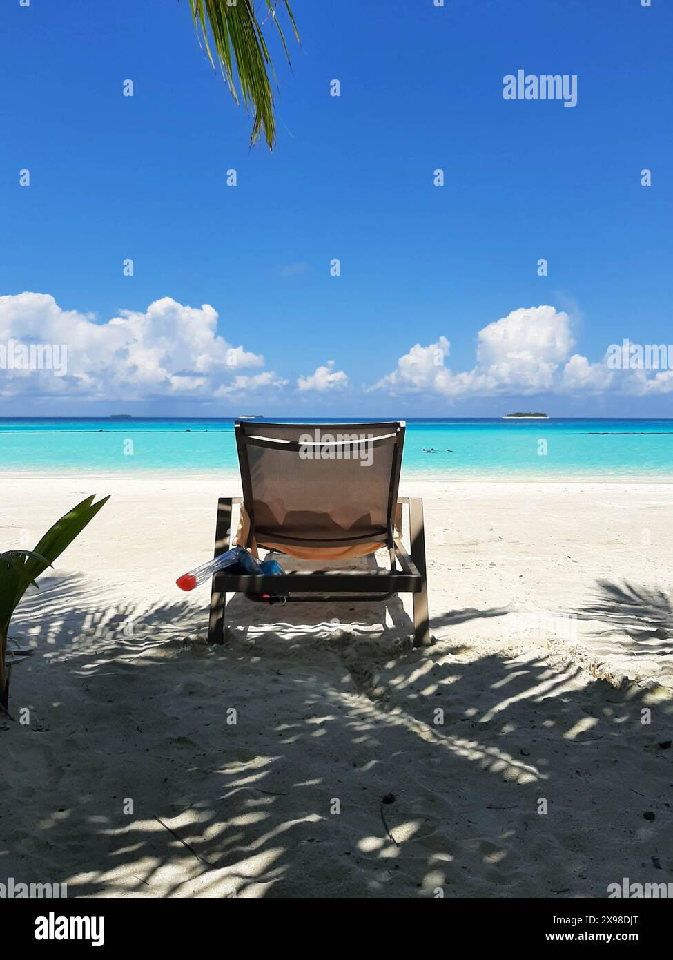 single wooden chair with a towel and a snorkel in a sandy beautiful beach with the sea in background, under a clear sky. holiday and vacation concept Stock Photo