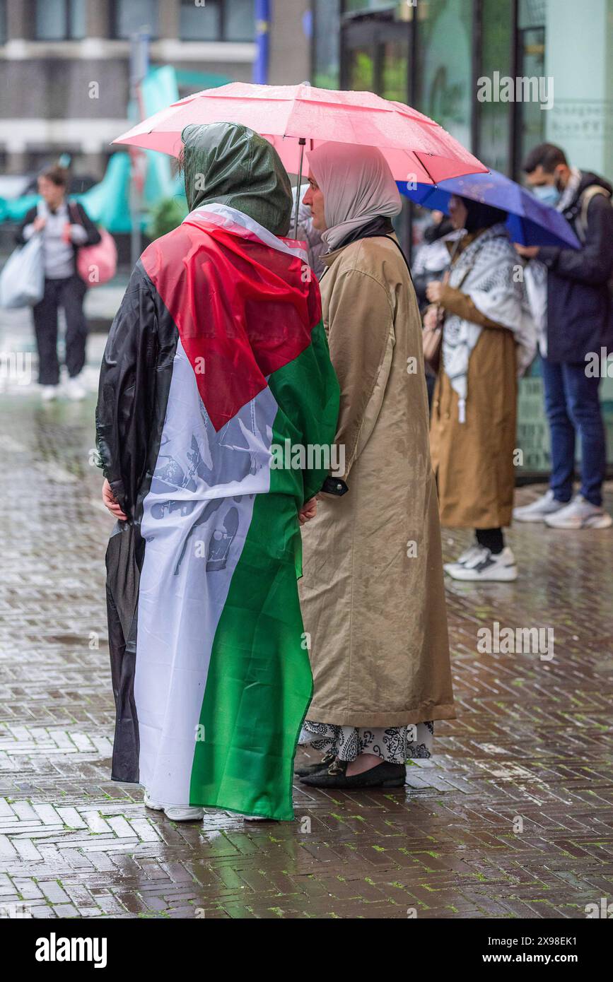 Two female support stand in umbrellas one draped in the national flag, during today's 'Hands of Rafah' demonstration in The Hague. A few hundred pro-Palestinian protesters stood opposite the 'Tweede Karmer' or, the 'Second Chamber' the Dutch seat of government in The Hague, during todayís 'Hands off Rafah - Where is your red line Rutte?'. The demonstrators stood in pouring rain, some with megaphones, and demanding the Dutch government change its stance in its support of Israel. The demonstration was in response to Rafah on Sunday, in which 45 people were killed, according to the Humas-run heal Stock Photo