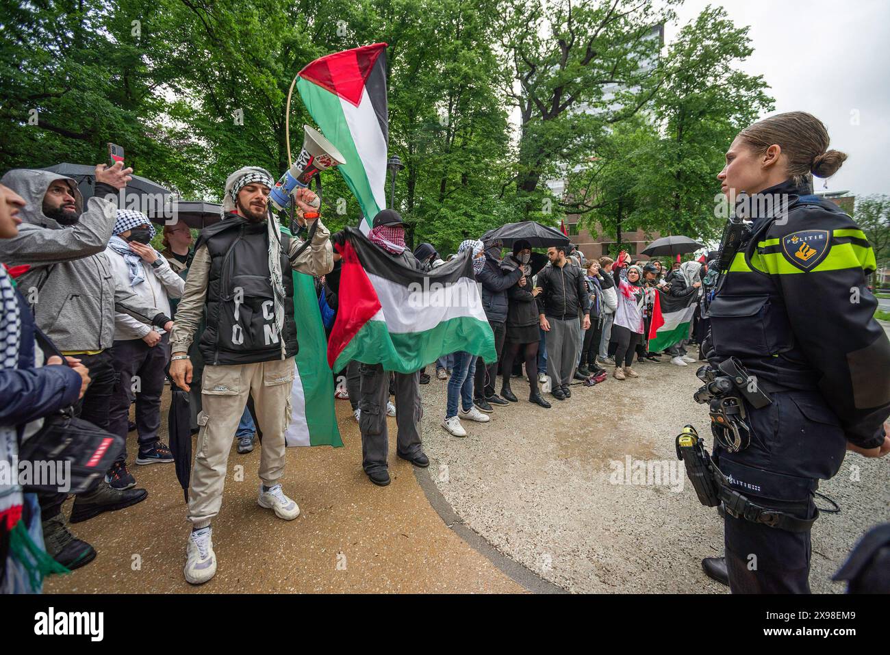 Pro-Palestinian demonstrators stand in front of police buffer line, during todayís ëHands of Rafahí demonstration in The Hague. A few hundred pro-Palestinian protesters stood opposite the 'Tweede Karmer' or, the 'Second Chamber' the Dutch seat of government in The Hague, during todayís 'Hands off Rafah - Where is your red line Rutte?'. The demonstrators stood in pouring rain, some with megaphones, and demanding the Dutch government change its stance in its support of Israel. The demonstration was in response to Rafah on Sunday, in which 45 people were killed, according to the Humas-run health Stock Photo