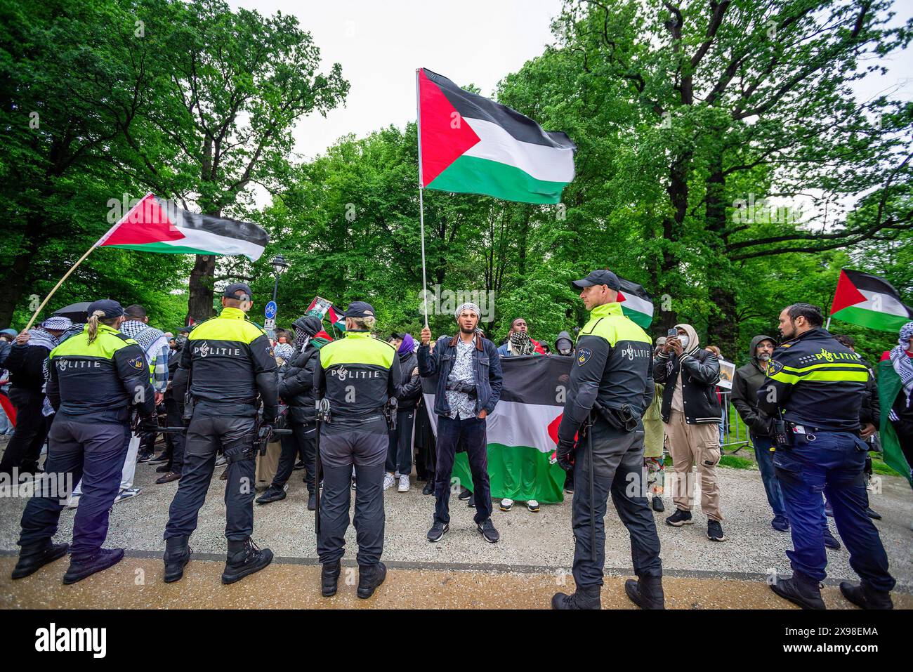 Pro-Palestinian demonstrators stand in front of police buffer line, during todayís 'Hands of Rafah' demonstration in The Hague. A few hundred pro-Palestinian protesters stood opposite the 'Tweede Karmer' or, the 'Second Chamber' the Dutch seat of government in The Hague, during todayís 'Hands off Rafah - Where is your red line Rutte?'. The demonstrators stood in pouring rain, some with megaphones, and demanding the Dutch government change its stance in its support of Israel. The demonstration was in response to Rafah on Sunday, in which 45 people were killed, according to the Humas-run health Stock Photo