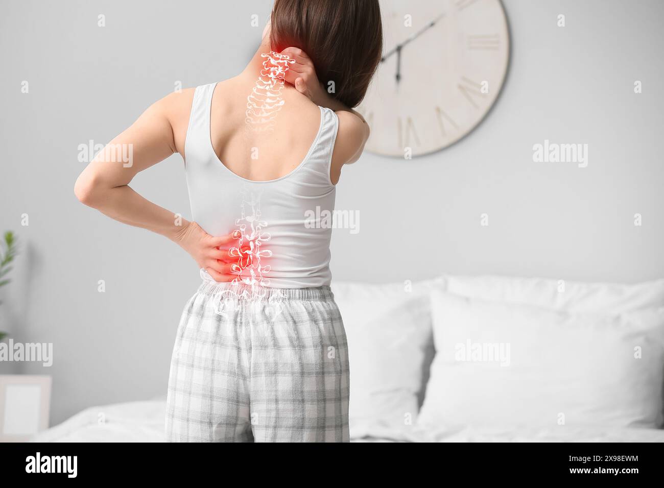 Young woman suffering from back pain in bedroom Stock Photo - Alamy