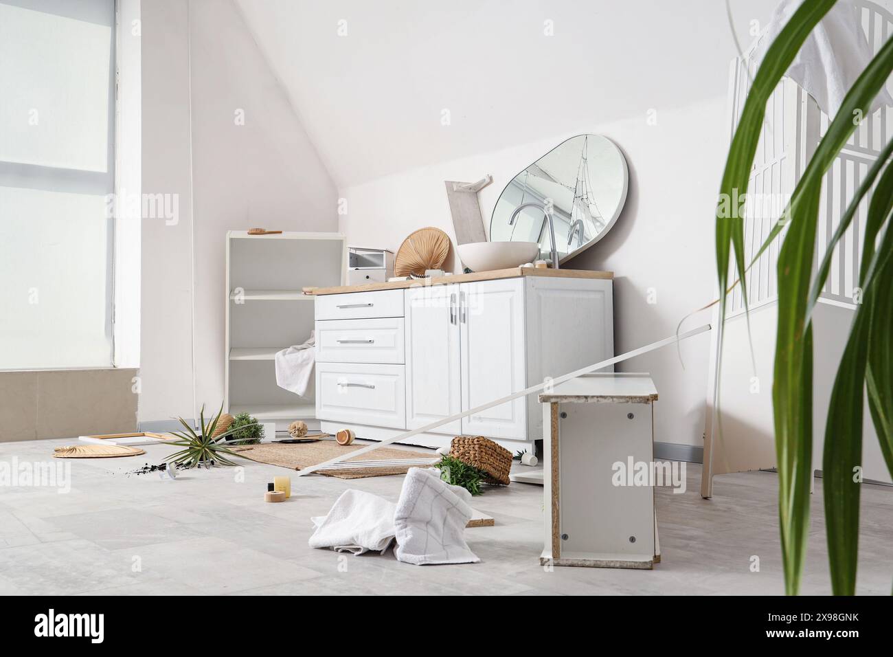 Counters with broken mirror and overturned things in messy bathroom Stock Photo