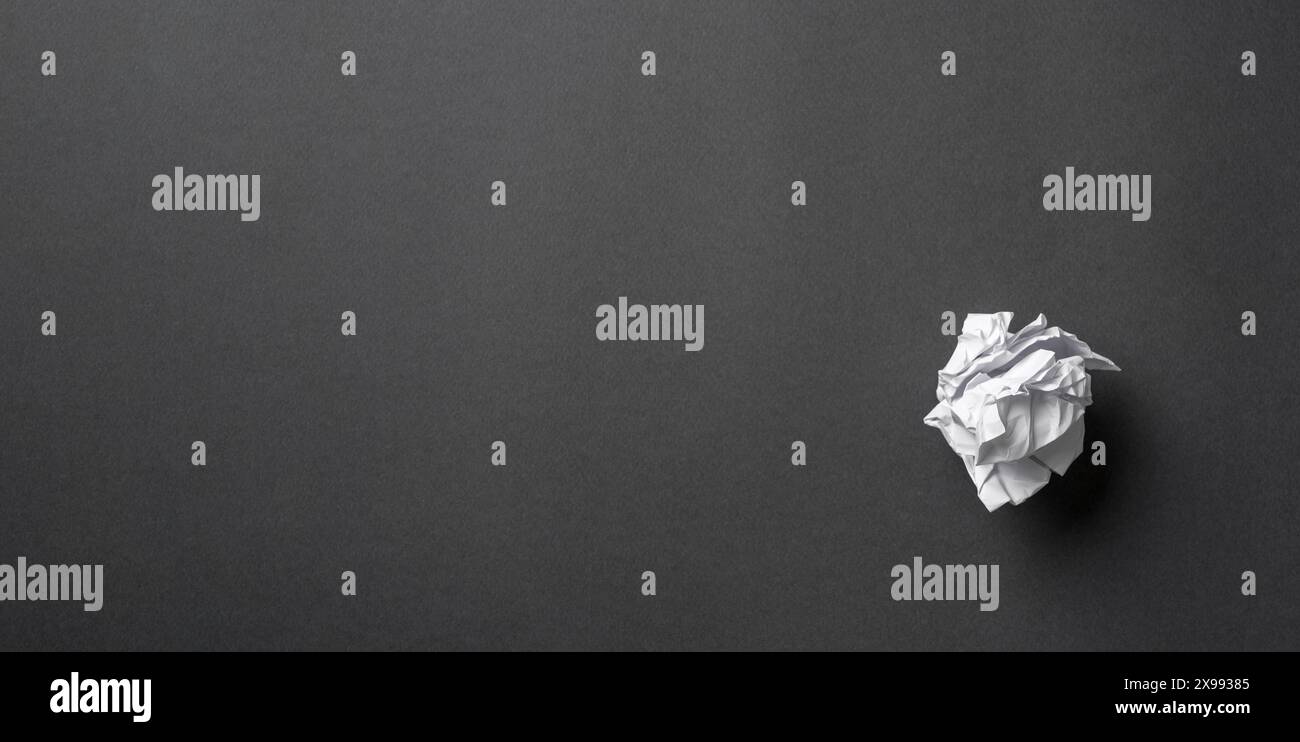 White paper crumpled into a ball on a dark gray background Stock Photo