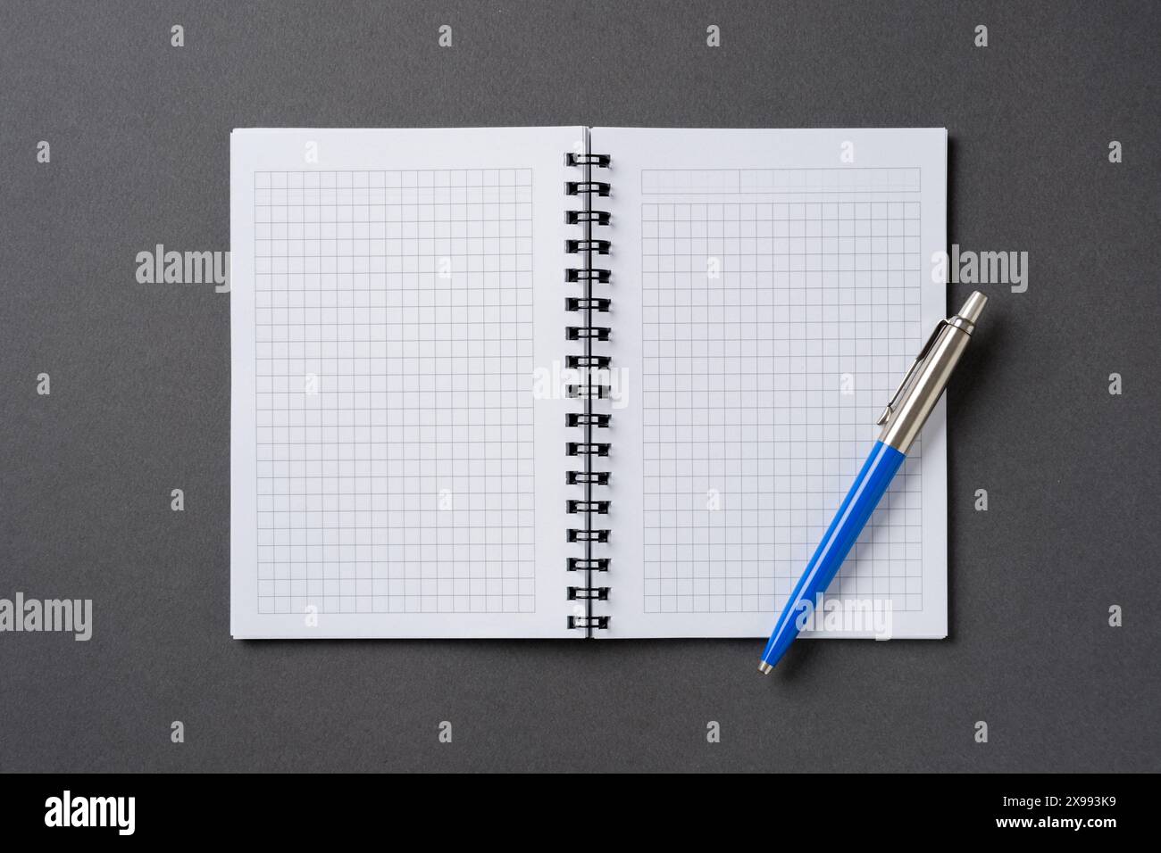 Open Notebook Chekered Checkered and spiral notebook on a dark gray table with a ballpoint pen ...