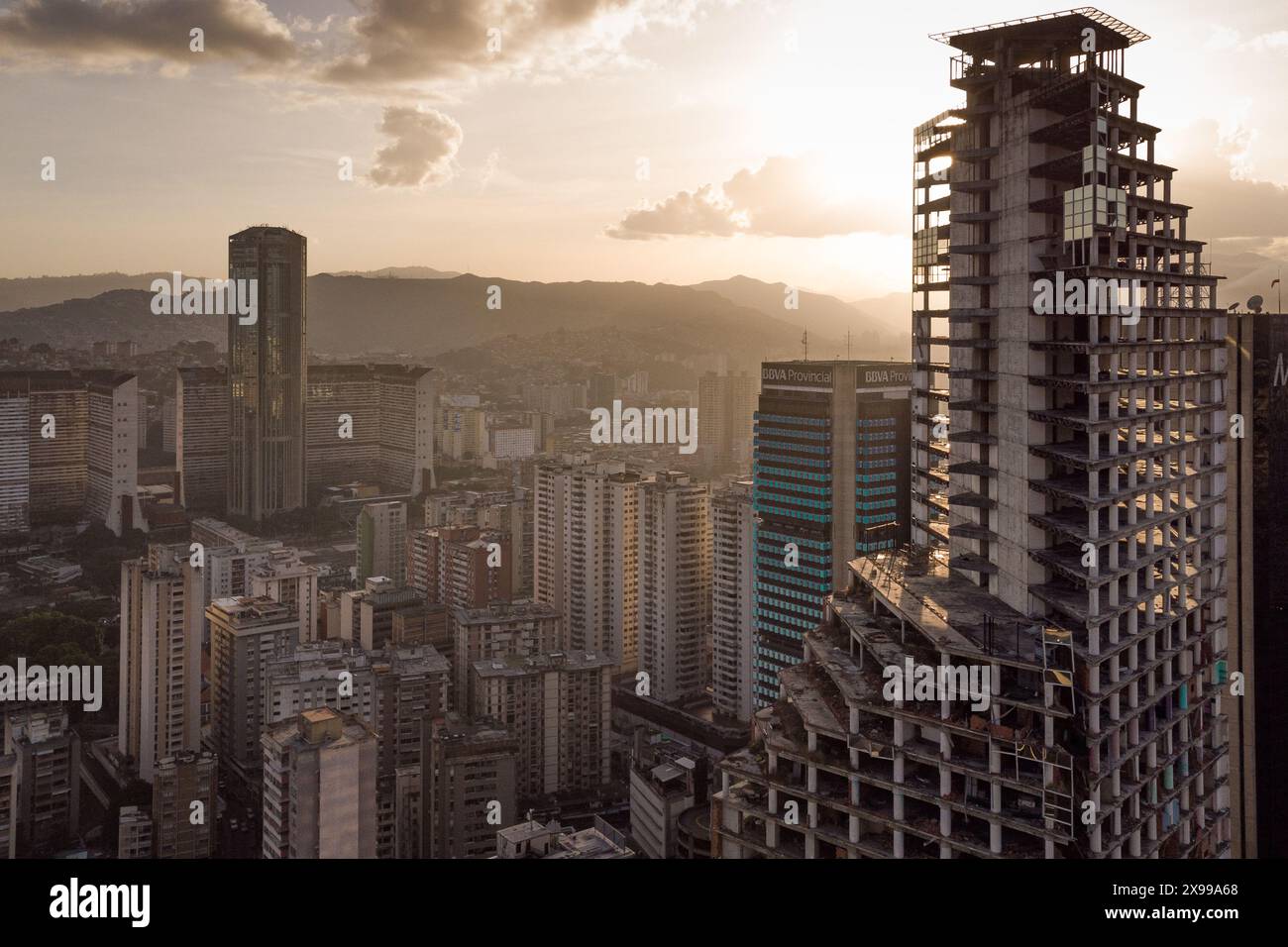 Aerial view of Caracas at sunset with the David Tower landmark skyscraper and slums visible. Drone shot of the venezuelan capital at sunset. Concept o Stock Photo