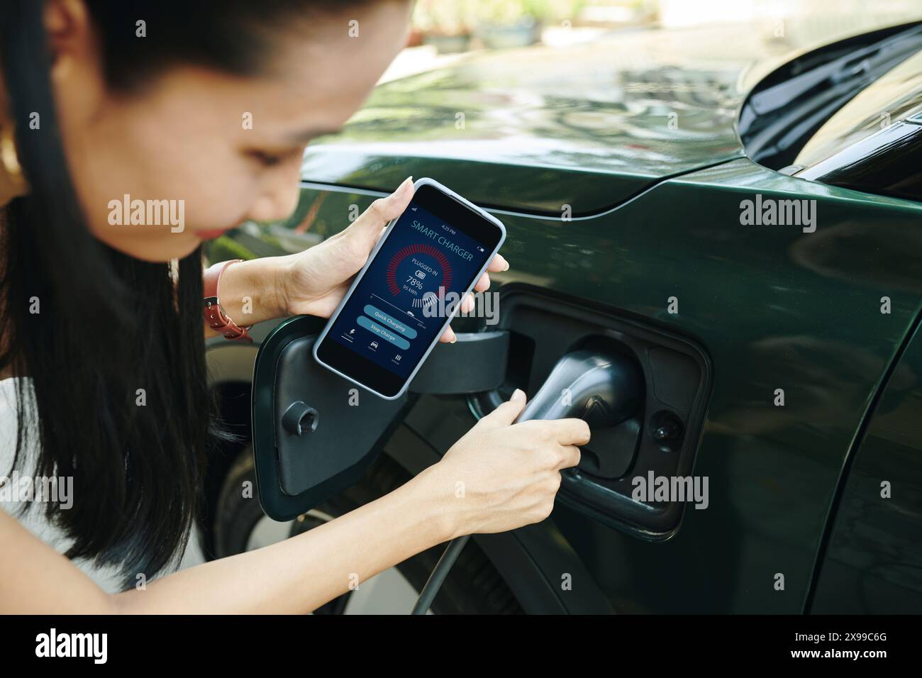 Cropped image of ev owner using smart charger app when charging electric car Stock Photo