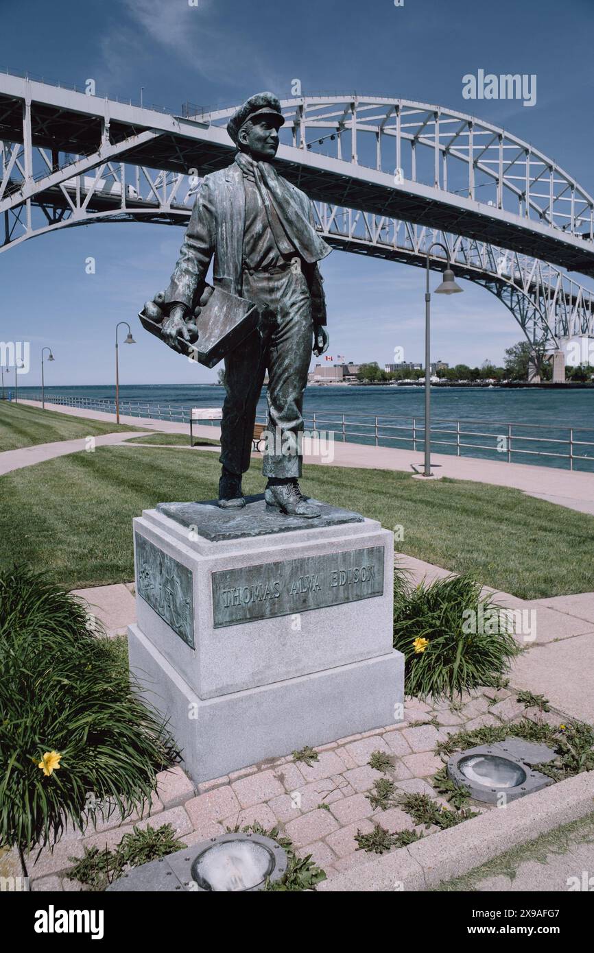 Thomas Alva Edison statue with the Blue Water Bridge in the background, Port Huron Michigan USA Stock Photo