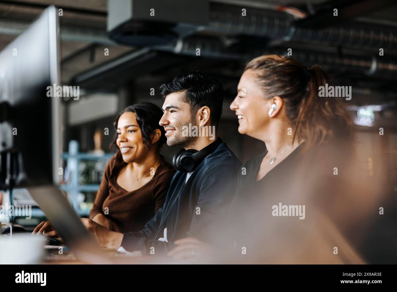 Smiling male and female computer programmers working together on computer at office Stock Photo