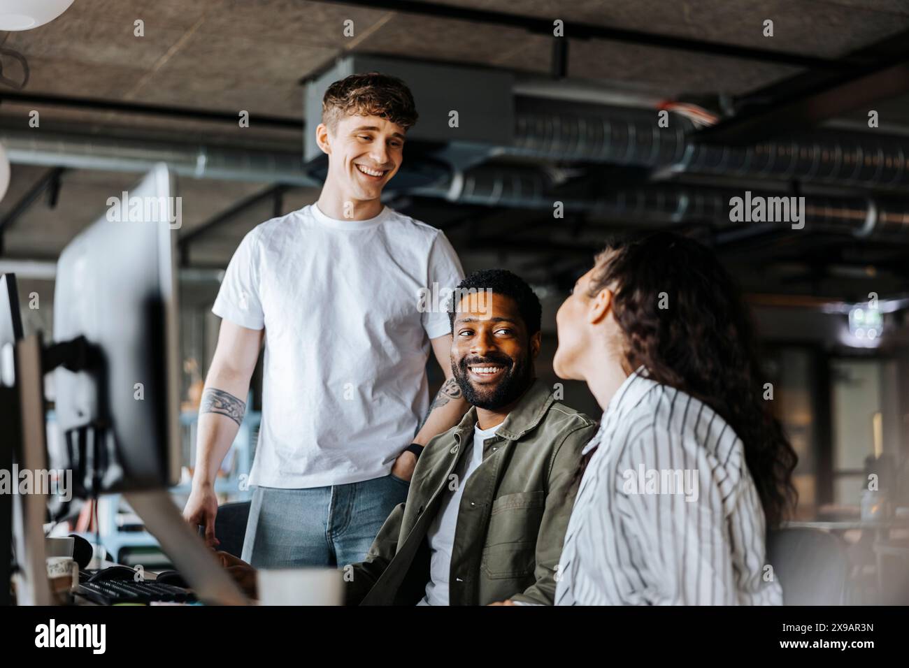 Smiling male entrepreneurs talking with female colleague at office Stock Photo