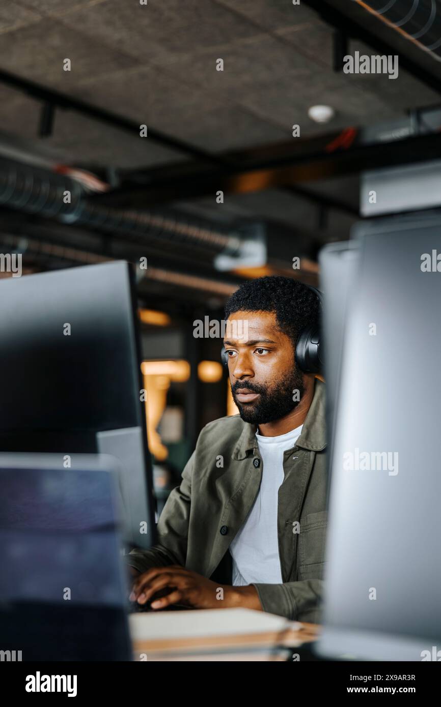 Serious male computer programmer working on computer at desk in office Stock Photo