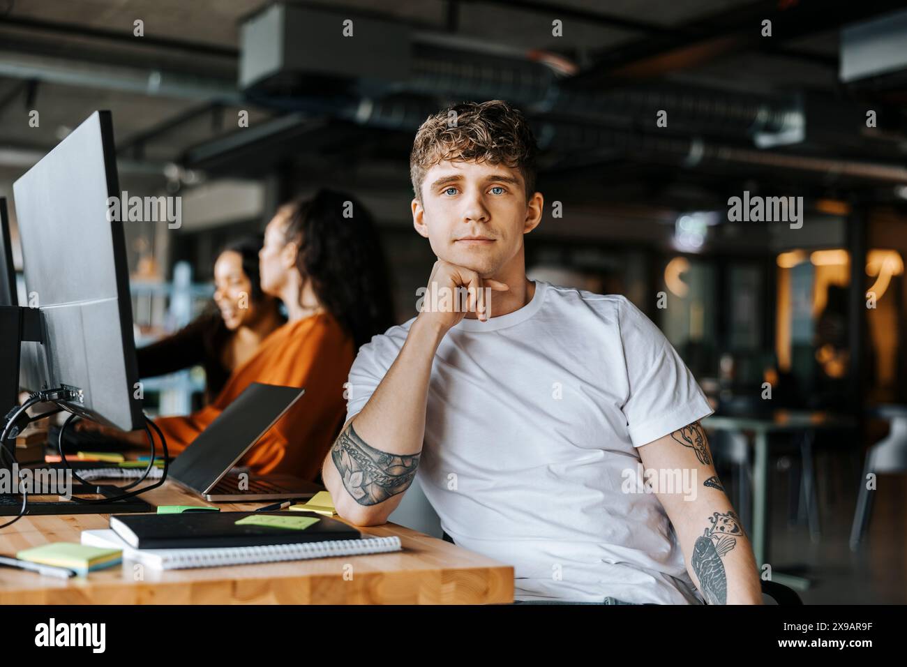 Portrait of male computer programmer leaning on elbow while sitting at ...