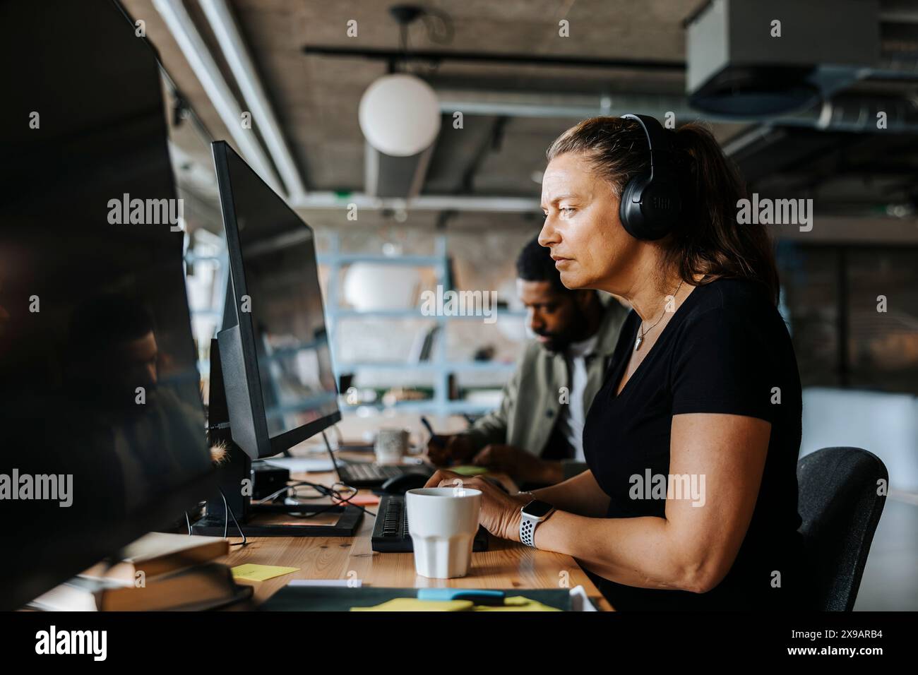 Focused female programmer coding while sitting at desk in tech start up office Stock Photo