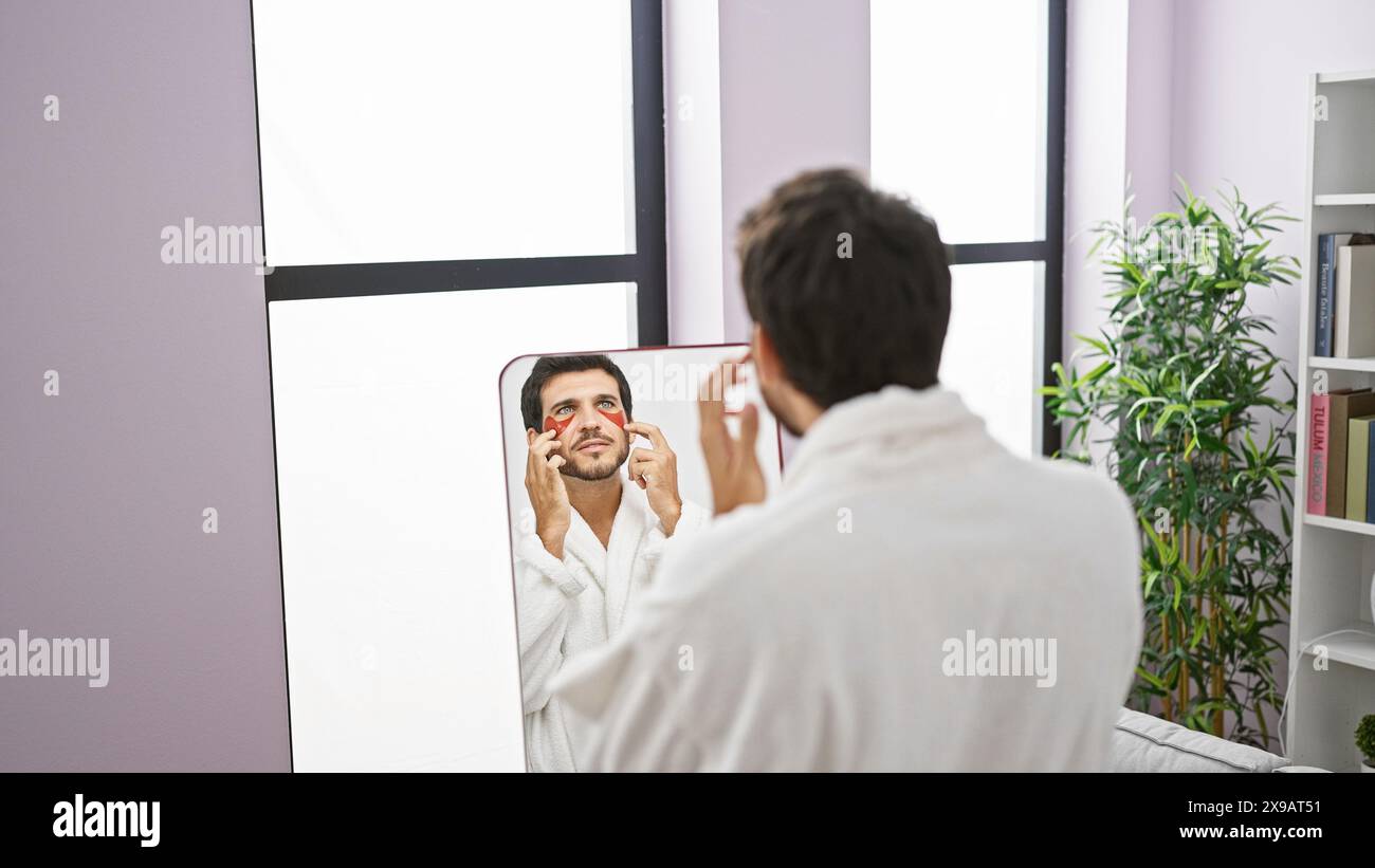 A bearded man in a white robe examines his face in the mirror of a well ...
