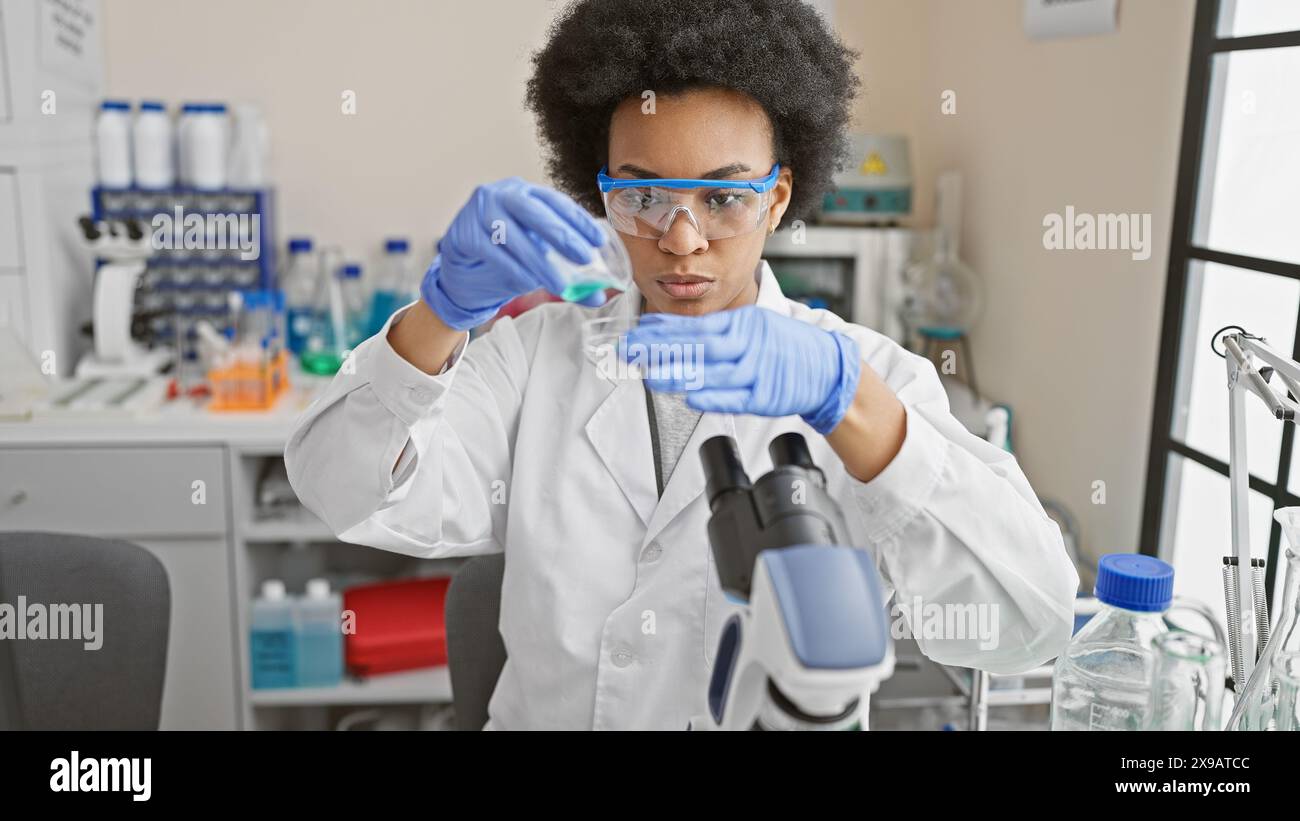 Focused african woman scientist examines test tubes in a laboratory setting, portraying professionalism and healthcare advancements. Stock Photo