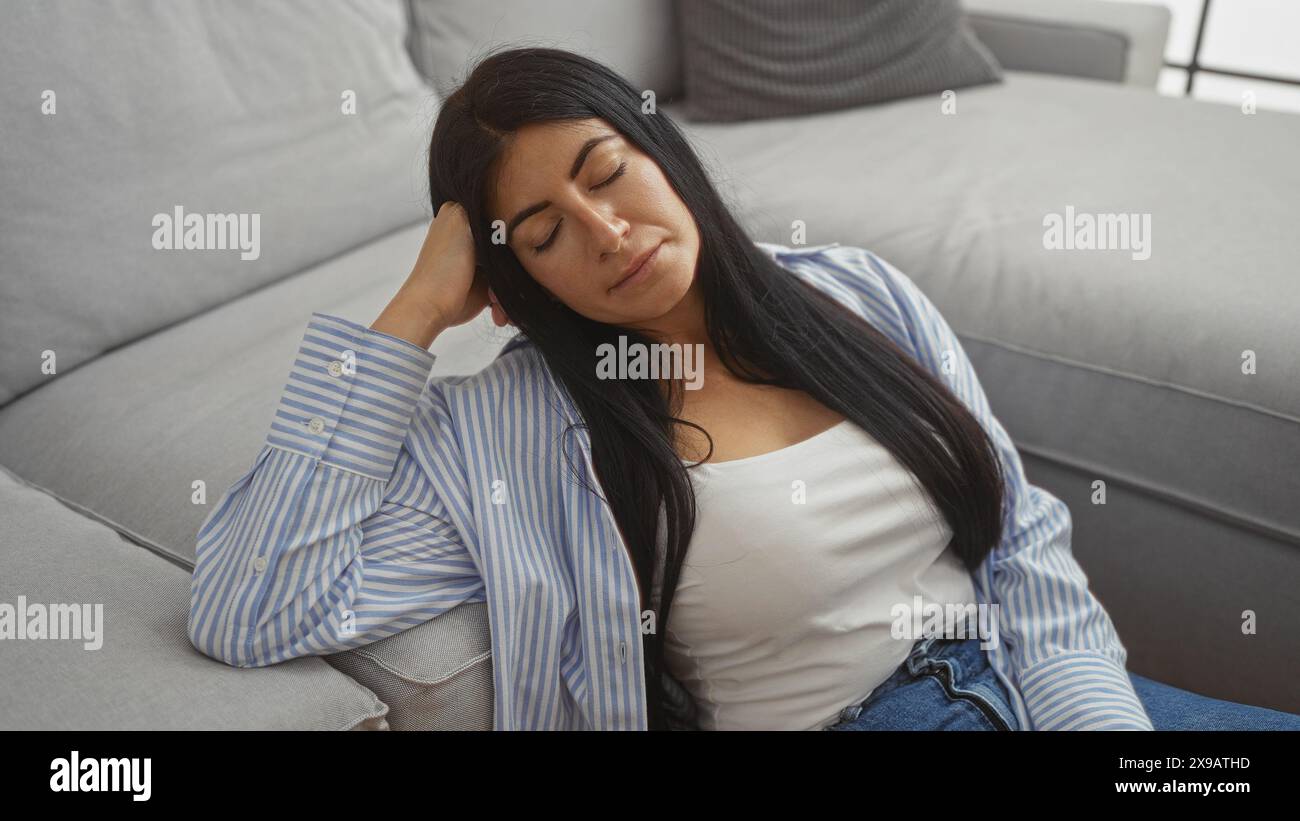 A beautiful young hispanic woman with brunette hair relaxes indoors on ...