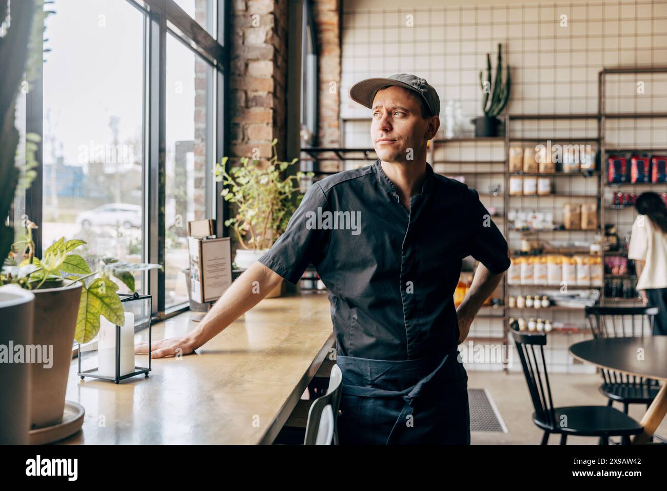 Male owner looking away while standing near table at coffee shop Stock Photo