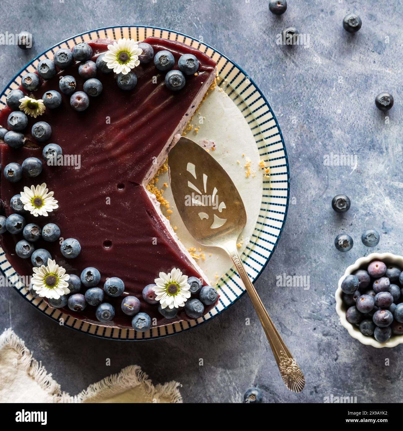 A homemade blueberry cheesecake garnished with blueberries and slices removed. Stock Photo