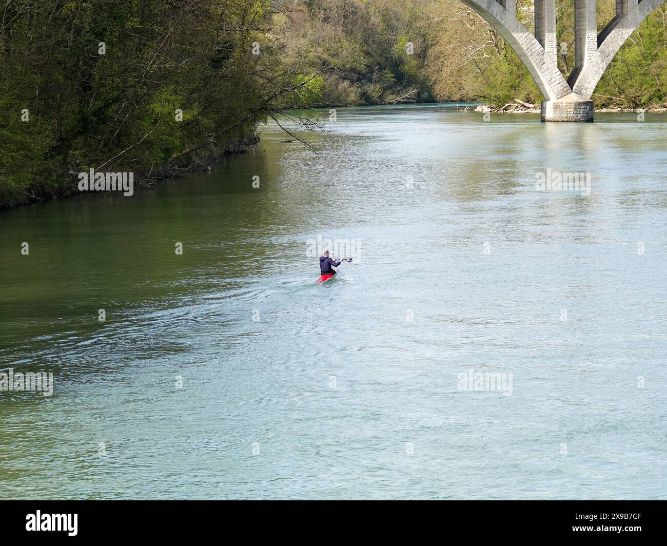 Lone kayaker paddles on the Arve River towards the confluence with the ...