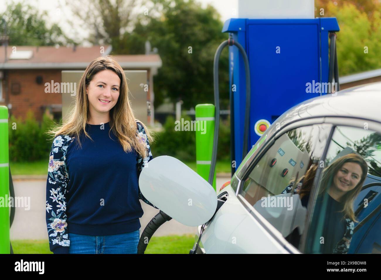 Woman inserts plug into the electric car charging socket Stock Photo