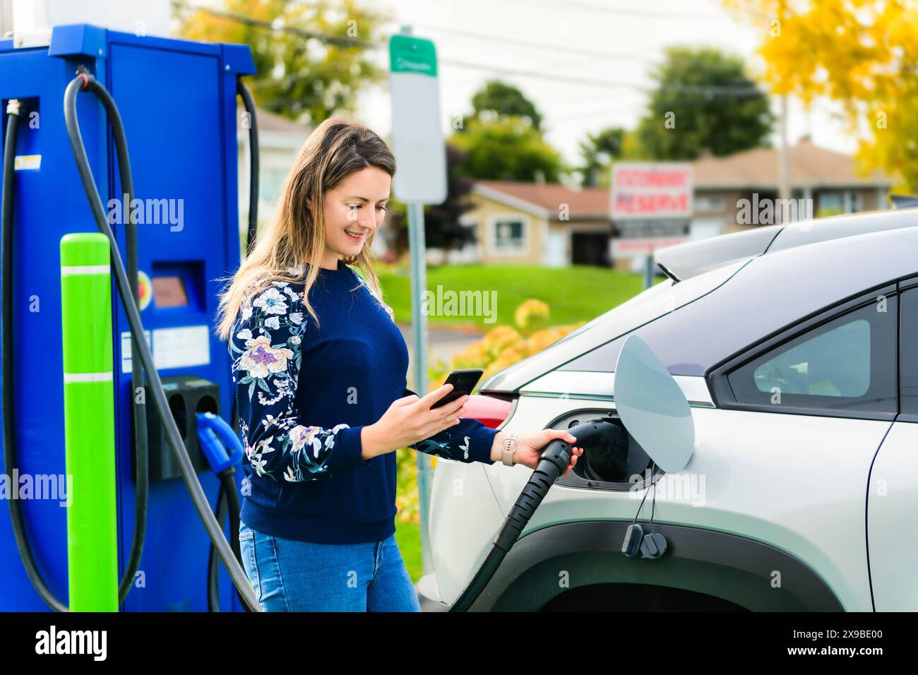 Woman inserts plug into the electric car charging socket Stock Photo