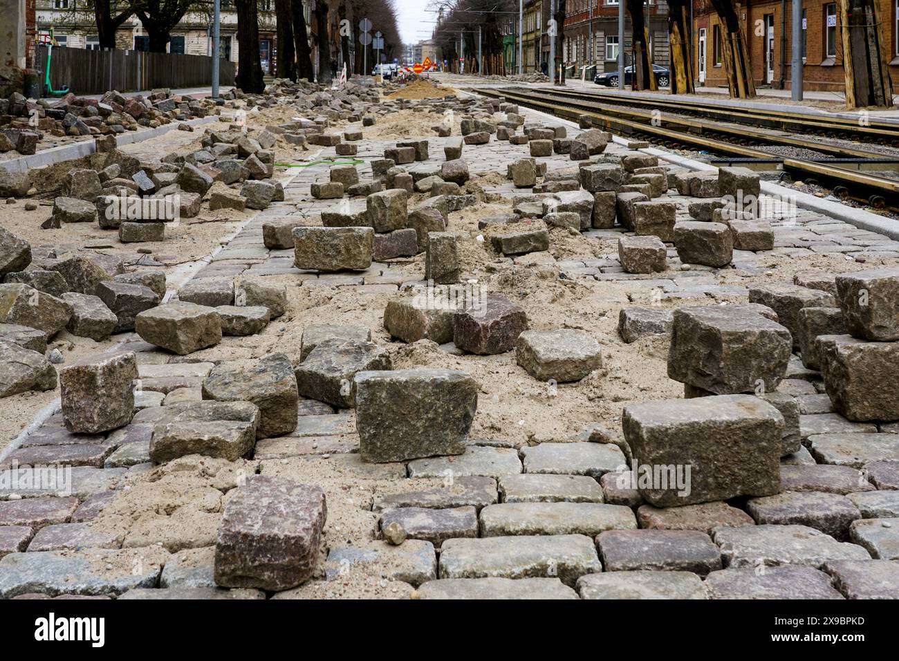 Close-up of historic cube-shaped hammered and chiseled natural granite paving stones on an unfinished street pavement Stock Photo