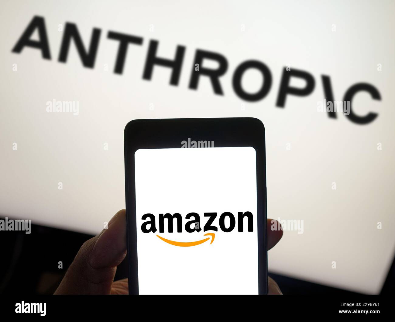 In this photo illustration, the Amazon logo is displayed on a smartphone screen and Anthropic logo background. Stock Photo