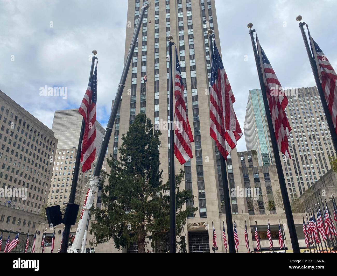 Several american flags waving in front of a skyscraper and other ...