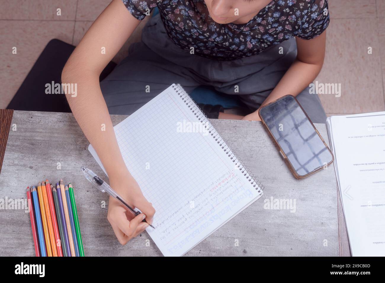 Close-up of the hands of a young woman doing homework, she writes in her notebook, homework topic. Stock Photo