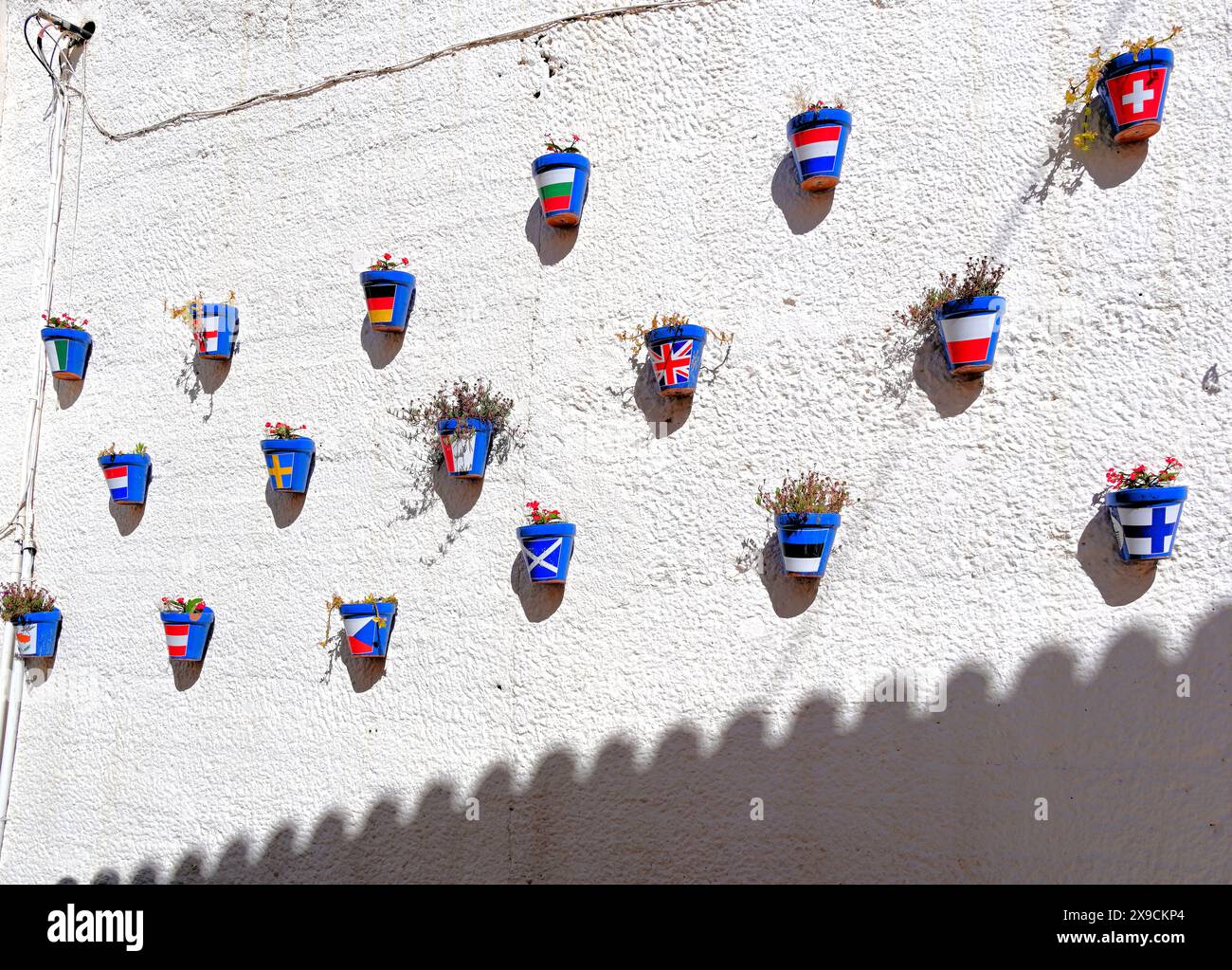 A white wall decorated with falg bearing flowerpots in the town of ...