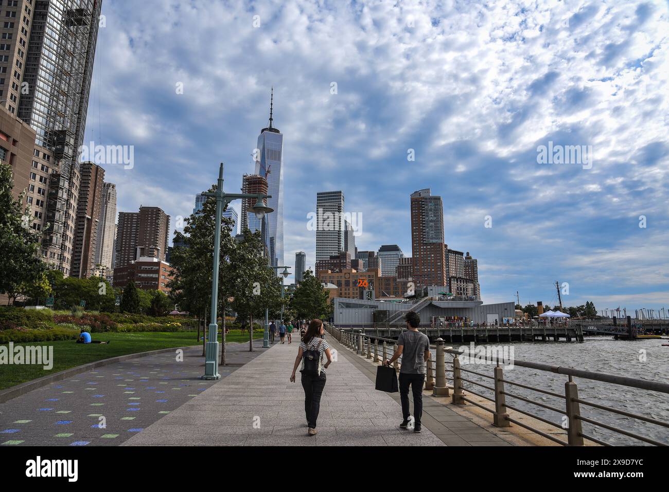 People strolling through Hudson River Park with One World Trade Center in the Background - Manhattan, New York City Stock Photo