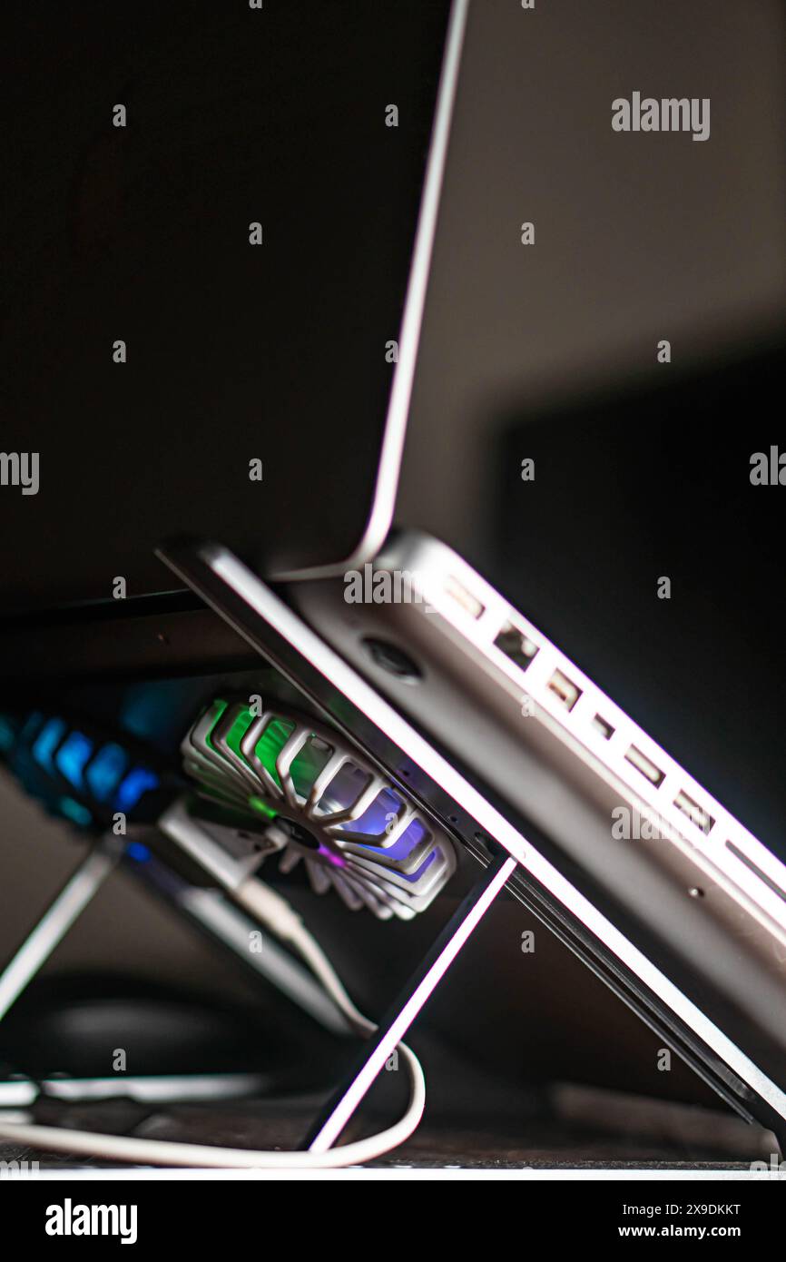 Close-up of a laptop on a stand with colorful cooling fans underneath ...