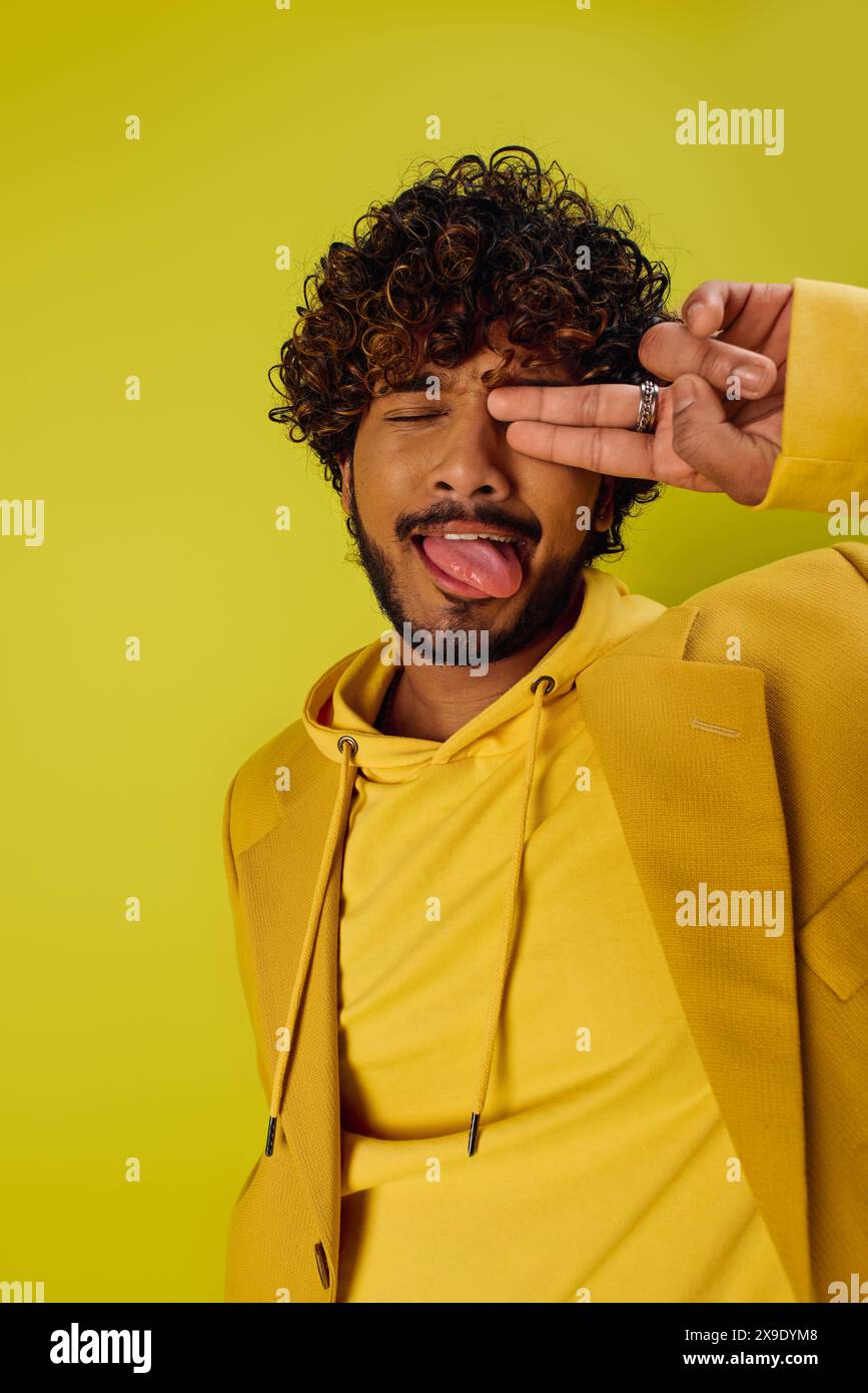 A handsome Indian man in a yellow hoodie makes a funny face. Stock Photo