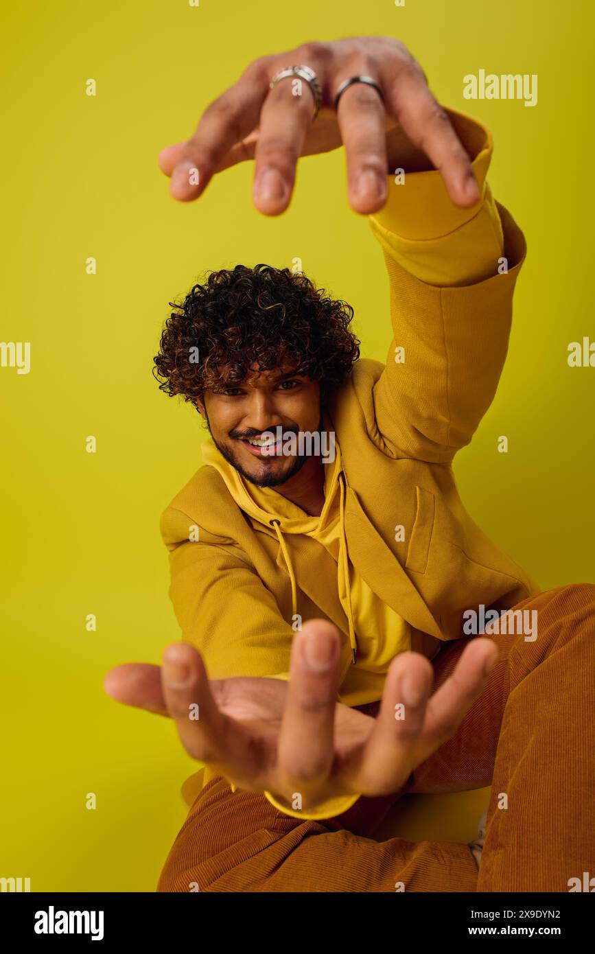 A man sitting on the ground with his hands raised in the air. Stock Photo