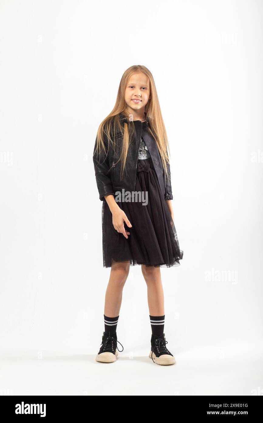 A full-length portrait of a young girl with long brown hair dressed in a hooligan style on white background in studio. Stock Photo