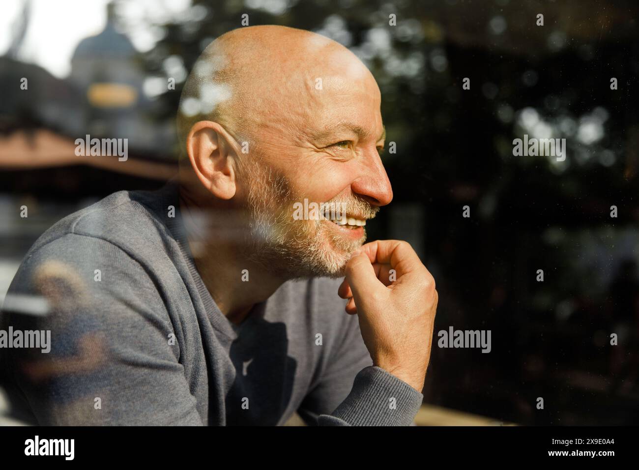 Elderly man with a thoughtful expression through a glass window Stock Photo