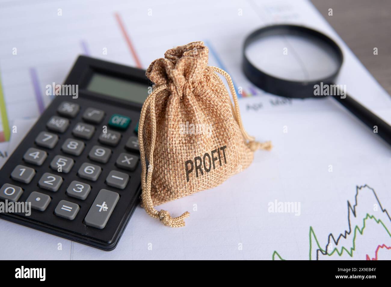 Money bag, calculator and magnifying glass on top of line graph ...