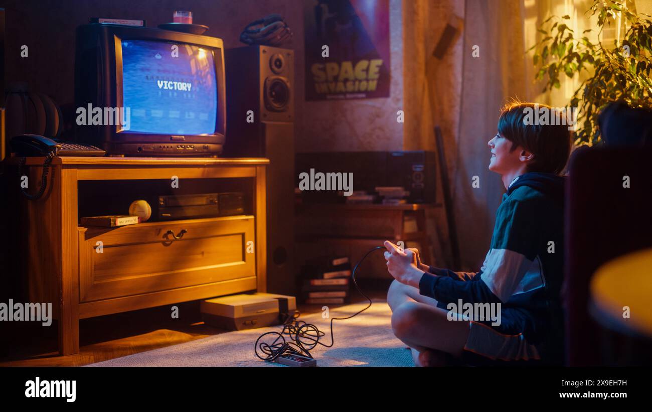 Young Boy Playing 80s Eight Bit Arcade Space Shooter Video Game on a Console at Home in His Vintage Room with Old-School Interior. Child Successfully Wins the Level. Nostalgic Retro Childhood. Stock Photo