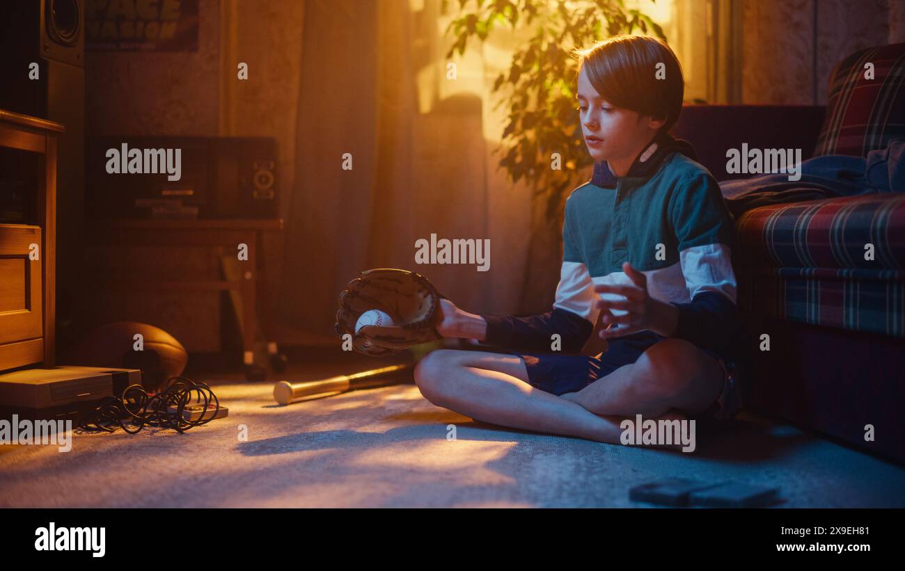 Young Sports Fan Playing with Baseball Ball and Glove at Home in Living Room with Vintage Interior. Excited Boy Having Fun and Enjoying Leisure Time in Nostalgic Retro Childhood Concept. Stock Photo