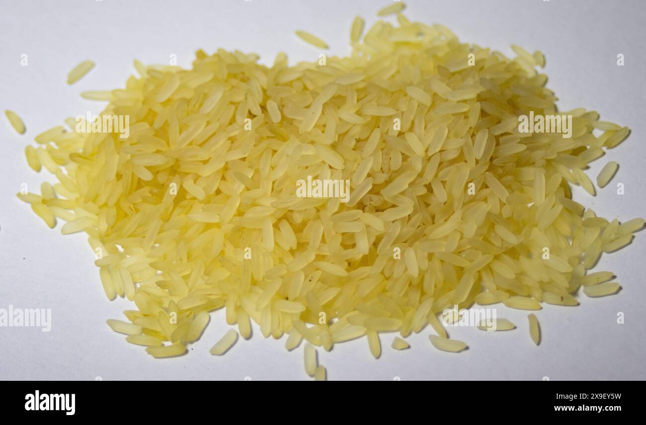 Very close-up photo of a pile of yellow parboiled rice on white ...