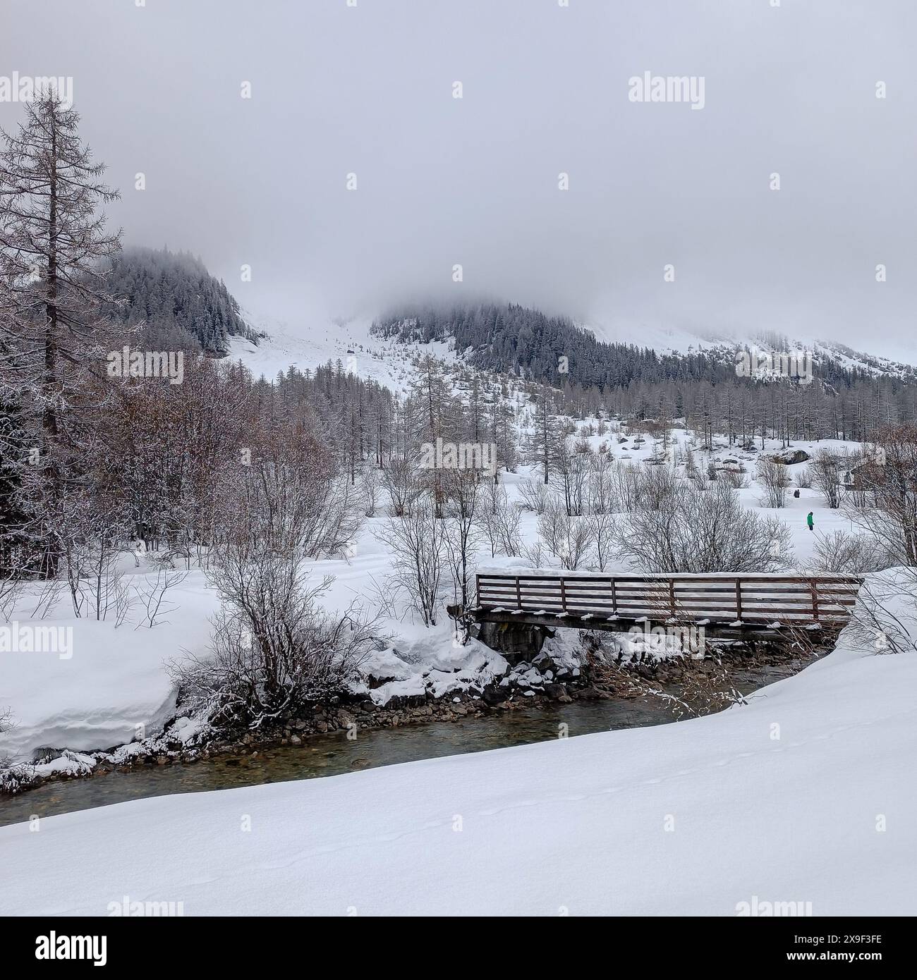 a wooden bridge crosses the river in the snowy valley Stock Photo - Alamy