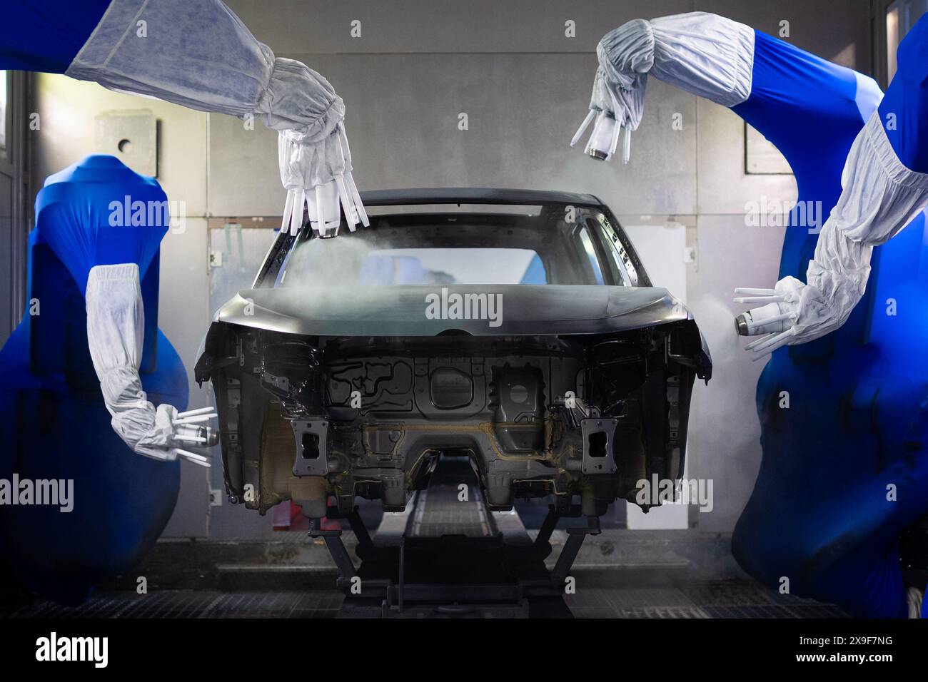 Wolfsburg, Germany. 23rd May, 2024. A Volkswagen is painted by robotic arms in a paint shop at the VW plant. Credit: Moritz Frankenberg/dpa/Alamy Live News Stock Photo