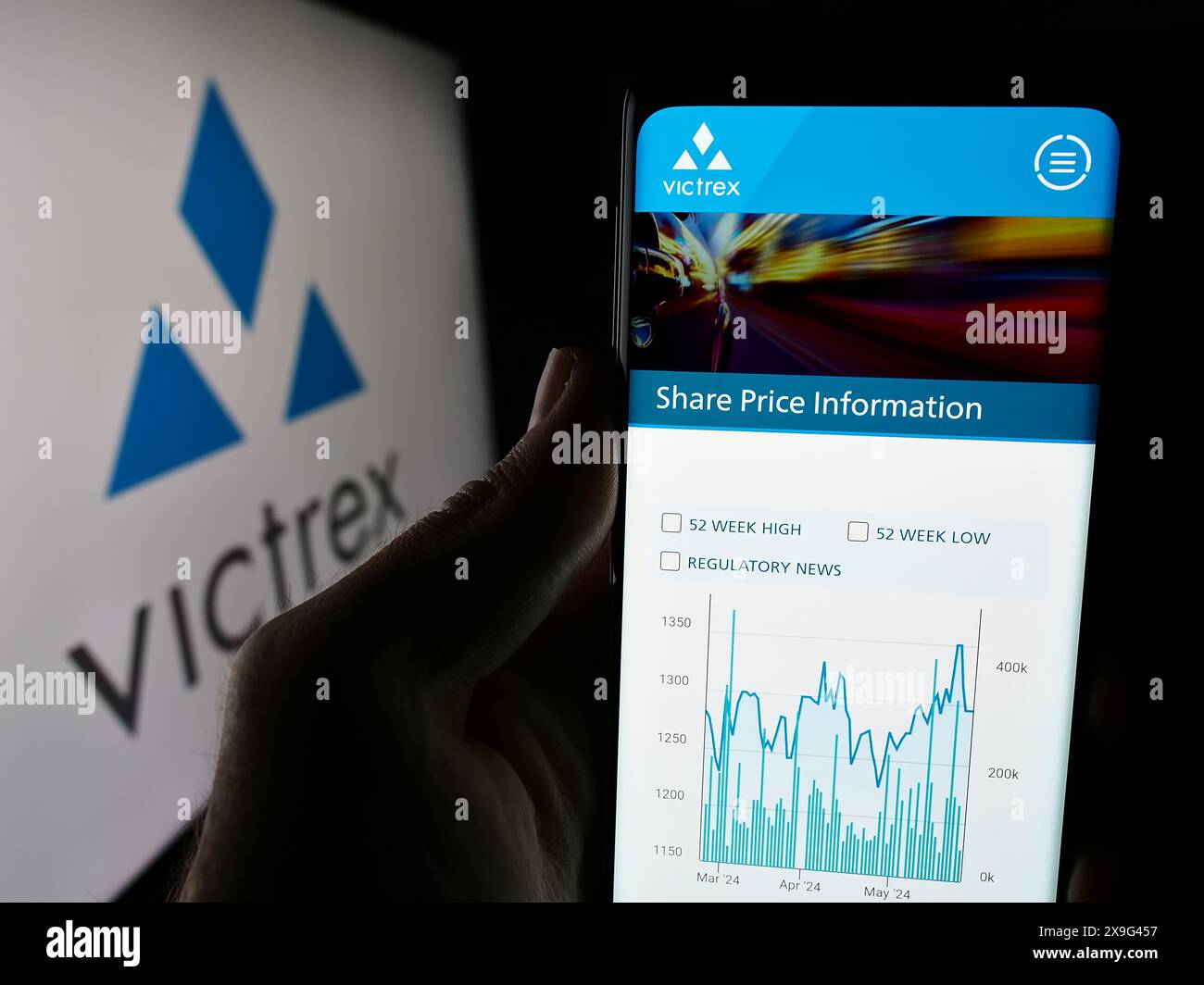 Person holding smartphone with website of British polymer production company Victrex plc in front of logo. Focus on center of phone display. Stock Photo