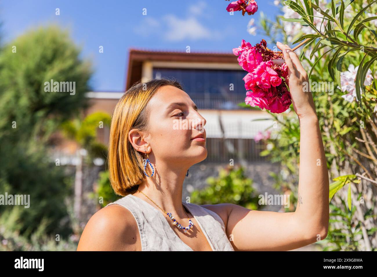 A woman is smelling a flower in a garden, spring season, blooming concept Stock Photo