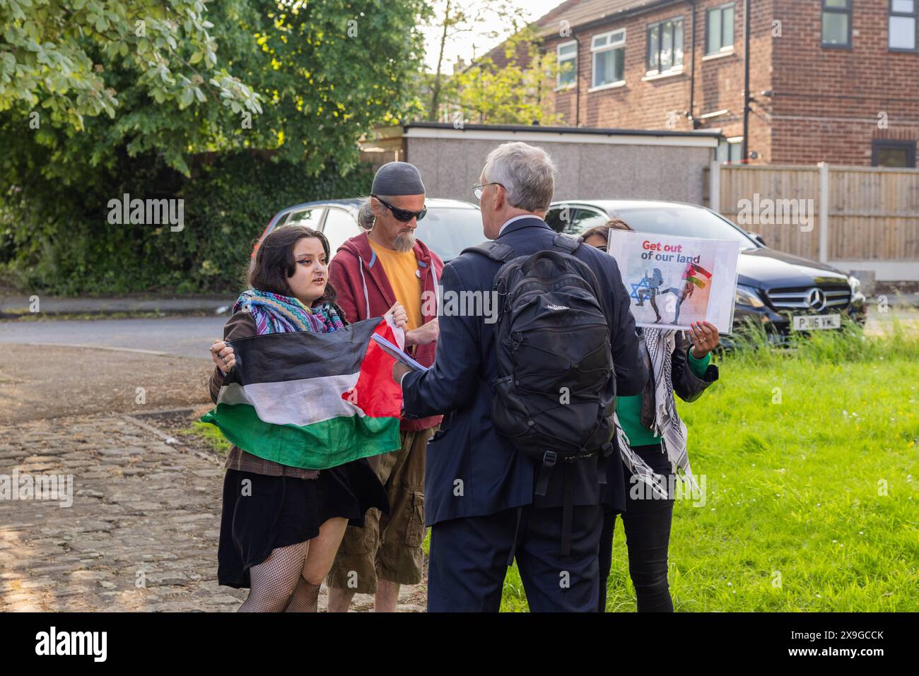 Leeds, UK. 31 MAY, 2024. Hilary Benn, Labour politician and candidate for Leeds South in the upcoming general election is confronted by Pro Palestine protestors while out door knocking in Halton. Benn spoke to the protestors for around 7 or 8 minutes before going back to door knocking. Conversation remained civil and both groups dispersed. Credit Milo Chandler/Alamy Live News Stock Photo