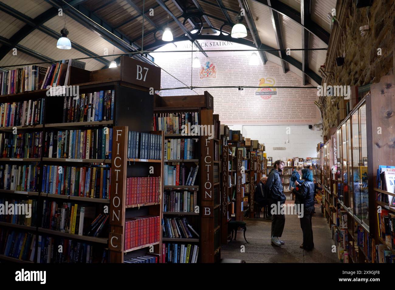 Customers chat in the aisles of Barter Books, famous and huge second hand bookshop based in former train station building in Alnwick Northumberland Stock Photo